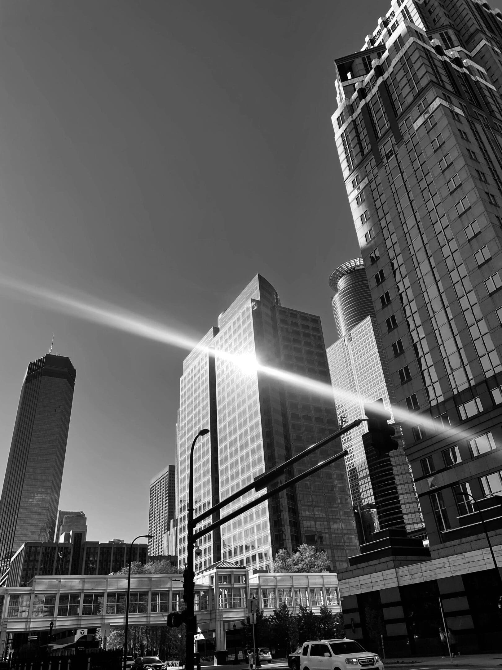 Sunlight reflects off tall skyscrapers in a bustling cityscape.