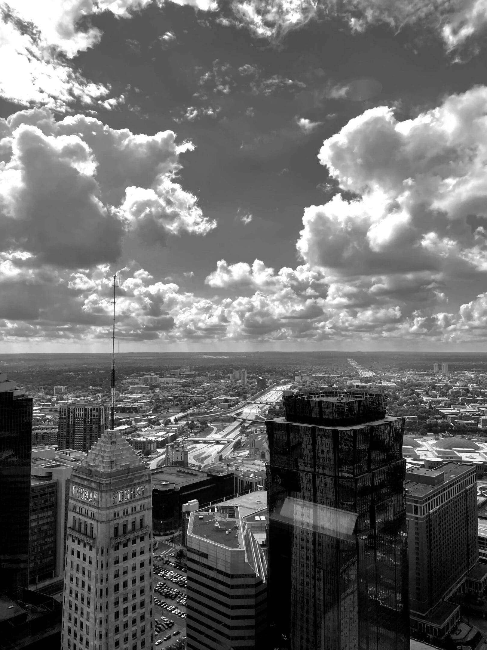 A city skyline with tall buildings under a dramatic cloudy sky.
