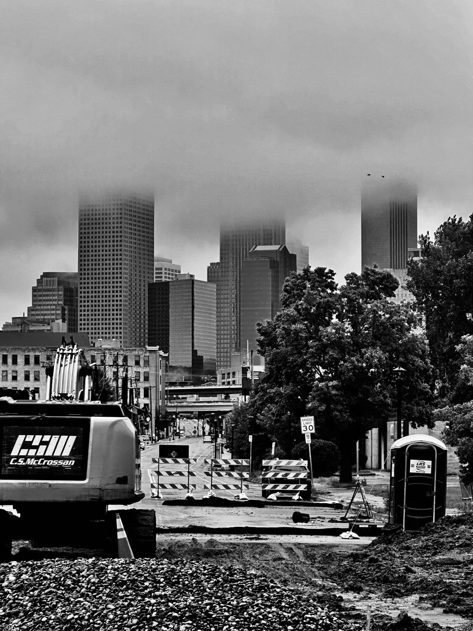 Foggy city skyline behind a construction site with barriers and equipment.
