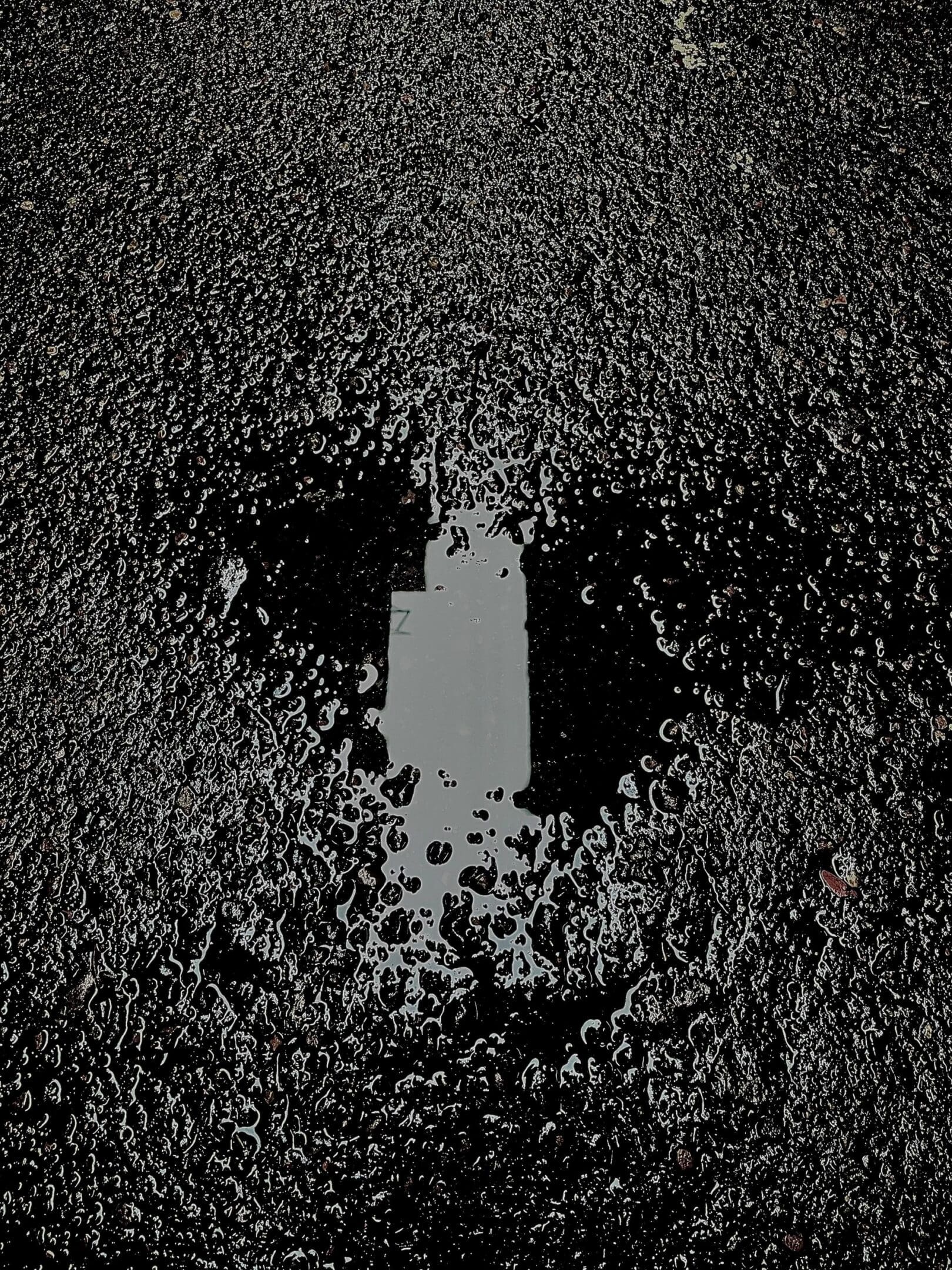 Reflection of a building in a rain puddle on asphalt.