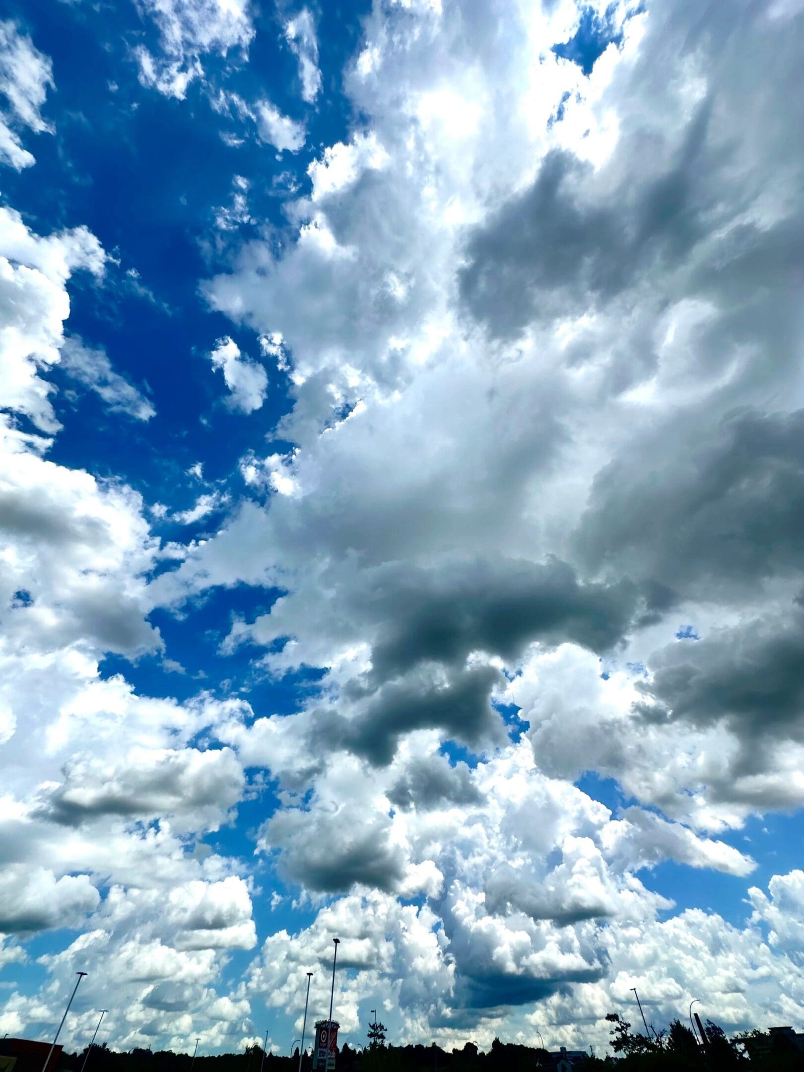 Dramatic sky filled with large, fluffy clouds over a silhouetted landscape.