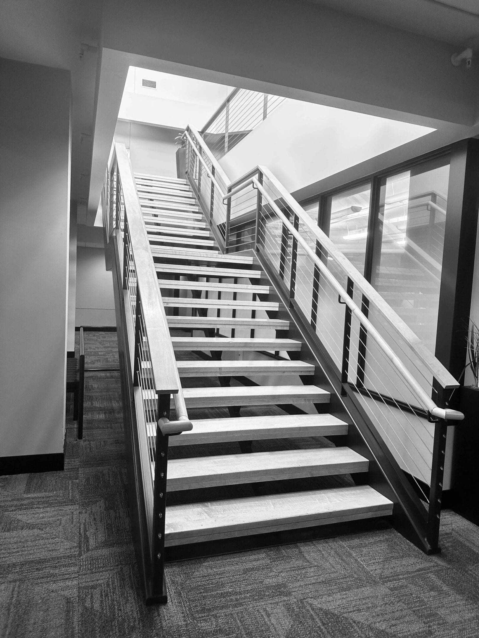 Modern indoor staircase with wooden steps and metal railings.