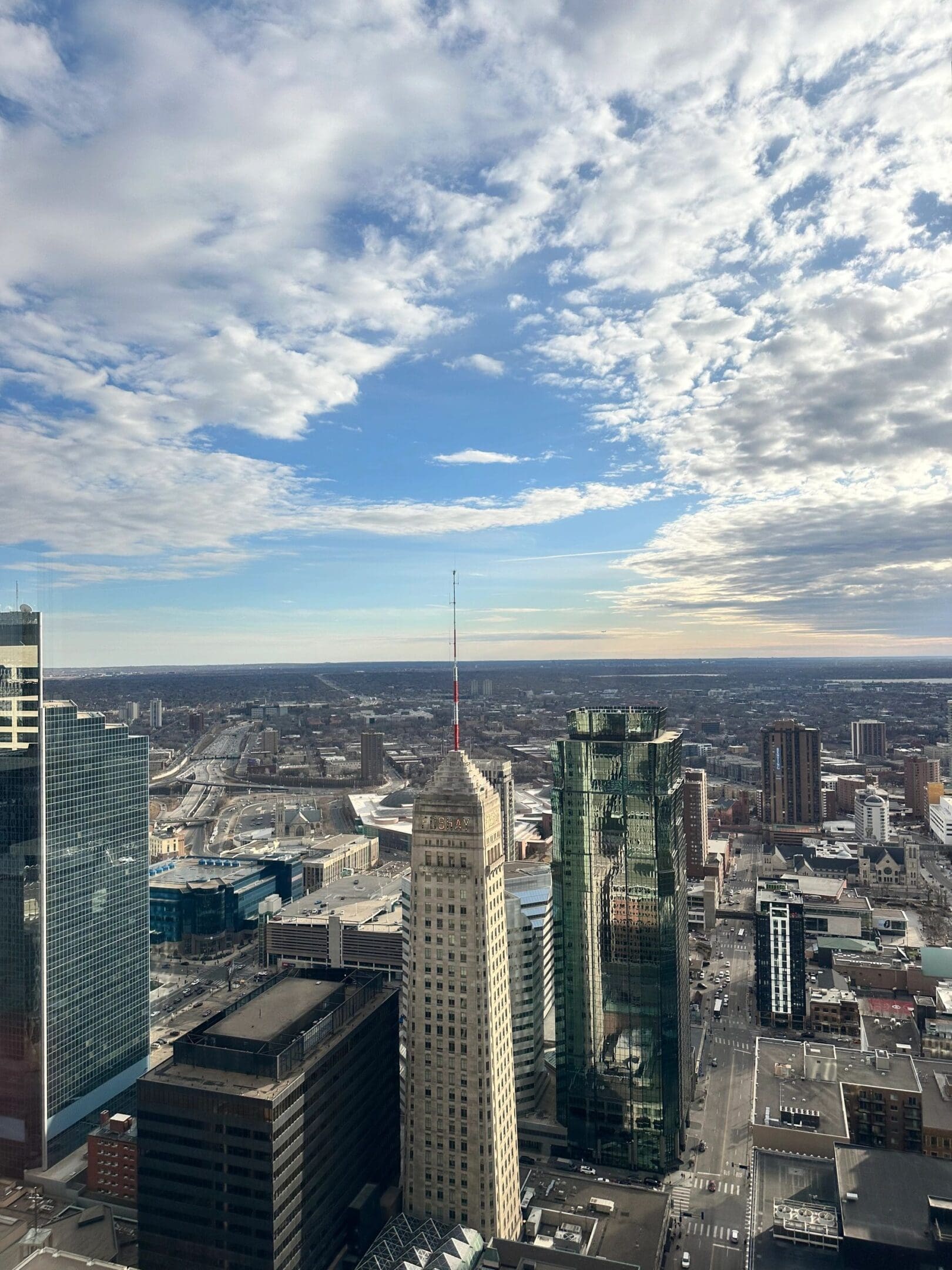 City skyline with tall buildings under a partly cloudy sky.