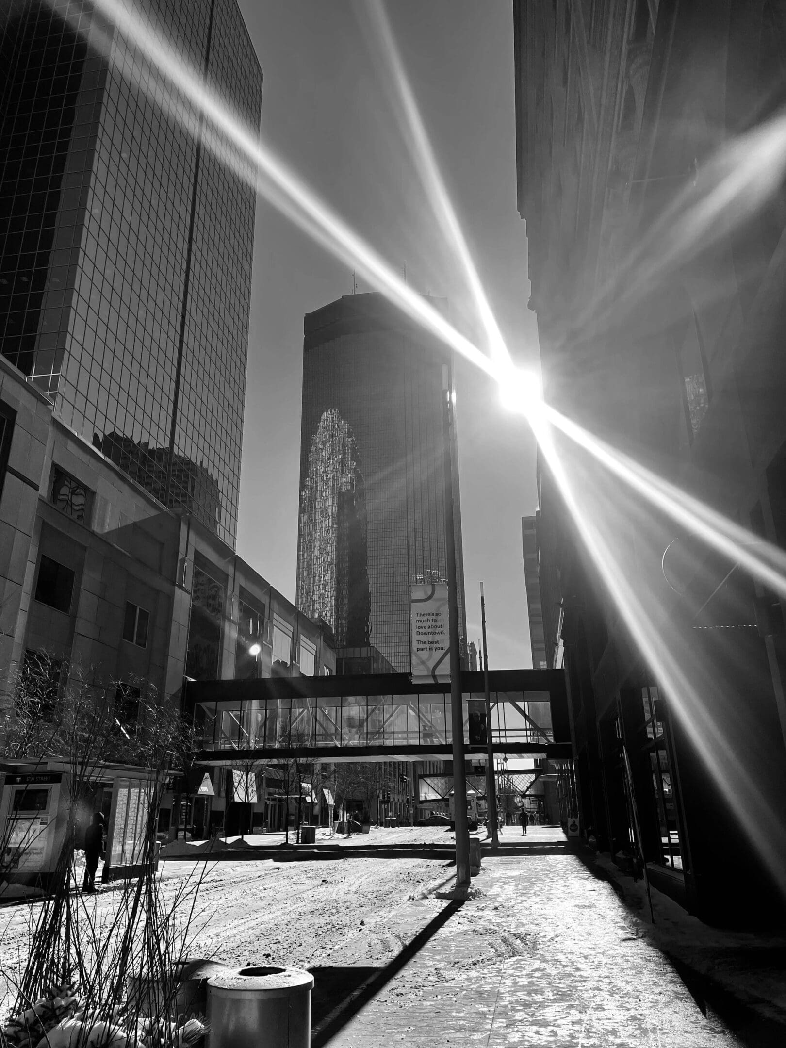 Sunlight beams cut through a city street with tall buildings casting long shadows.